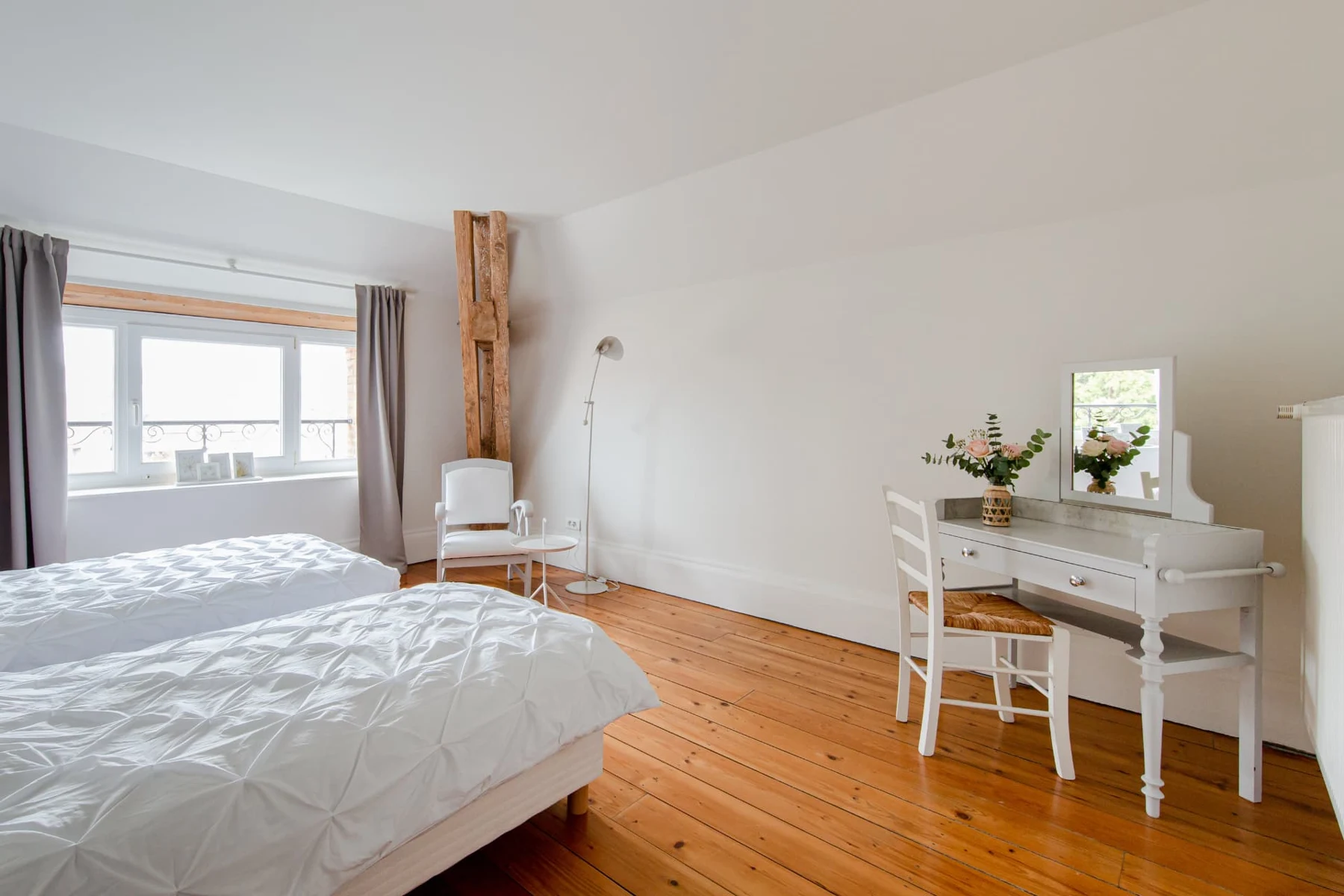 Chambre aux deux lits blancs, coiffeuse ancienne à miroir et parquet clair