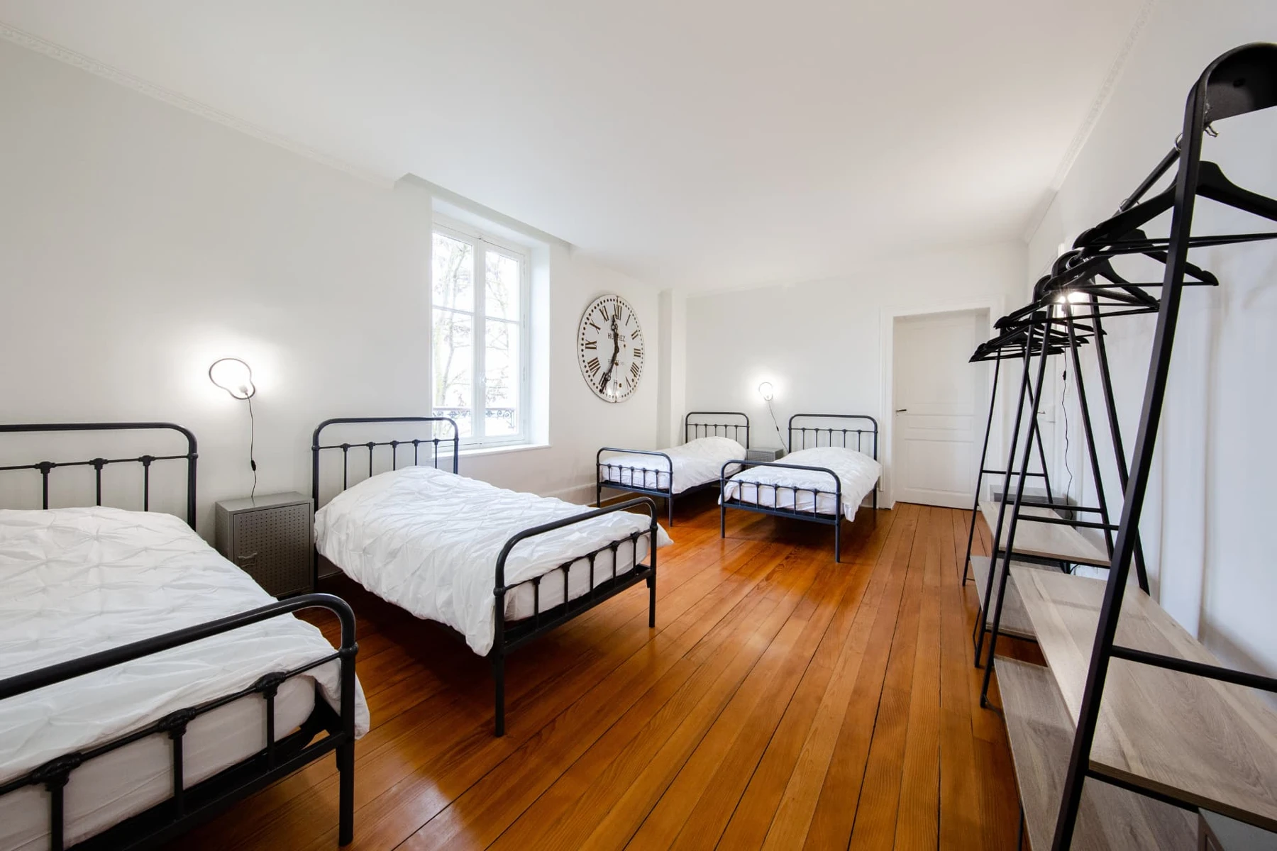 Chambre 4, lits en métal noir, grande horloge murale et parquet ancien