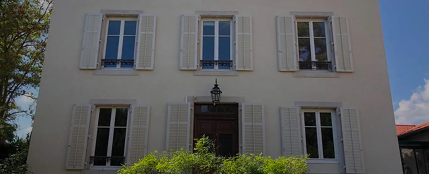 Façade blanche de la Maison 1881 et ses volets, à Tonnoy