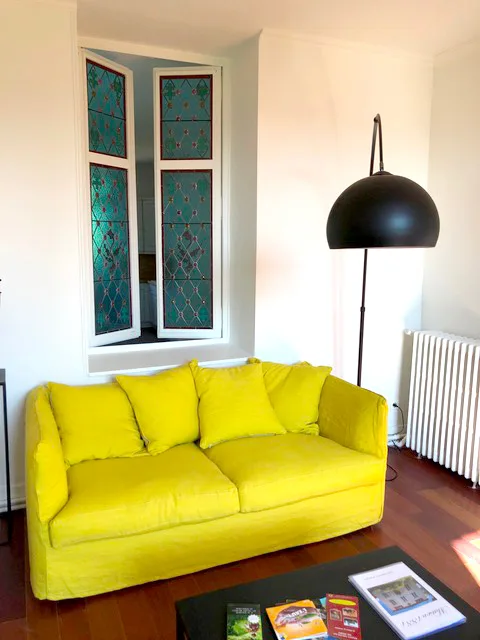 Salon lumineux, fauteuils noirs et poêle en fonte
