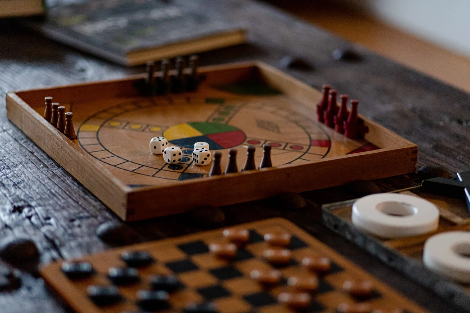 Jeux de société en bois sur la grande table : petits chevaux, dames et morpion géant
