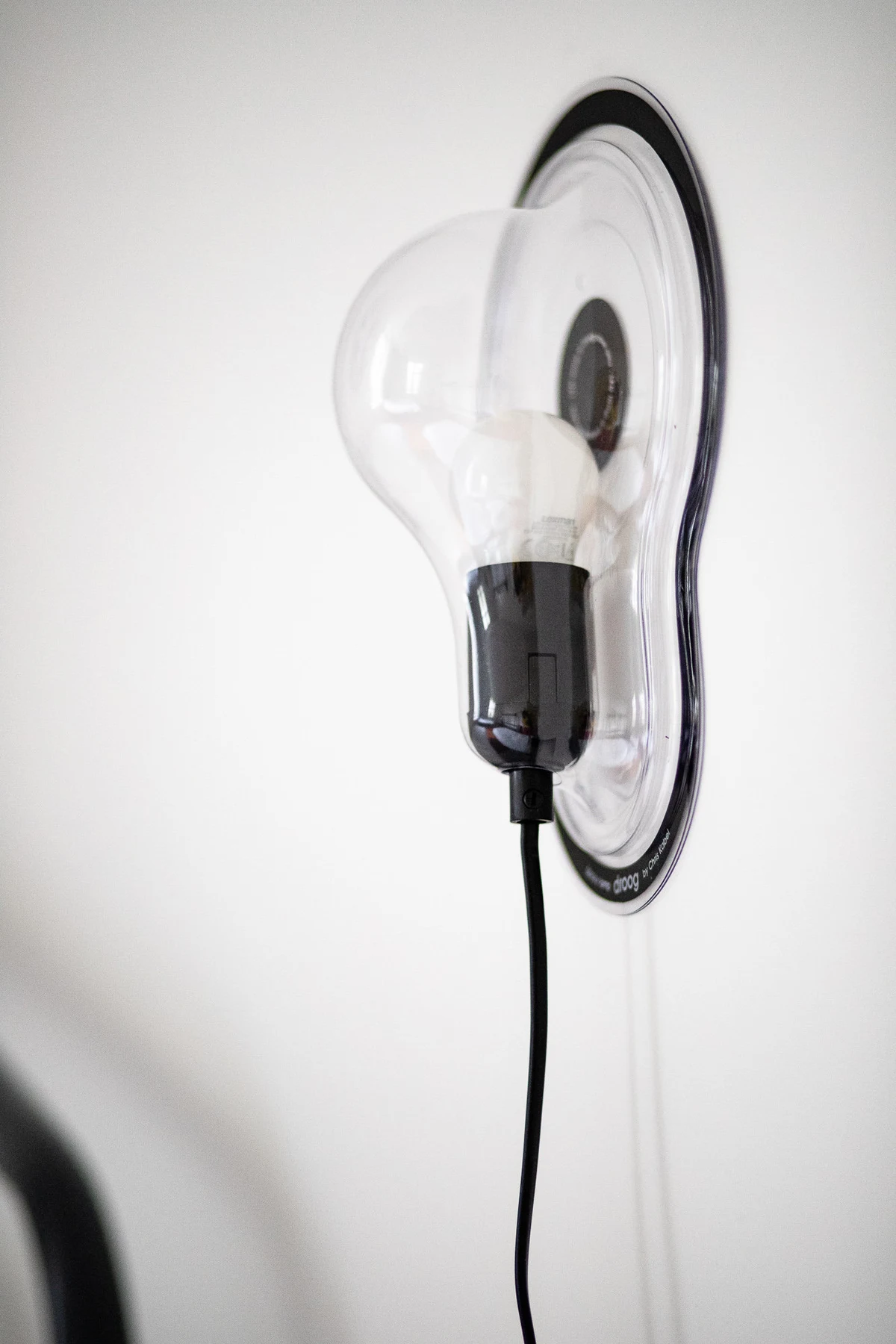 Applique au design d'ampoule géante en verre transparent sur un mur blanc