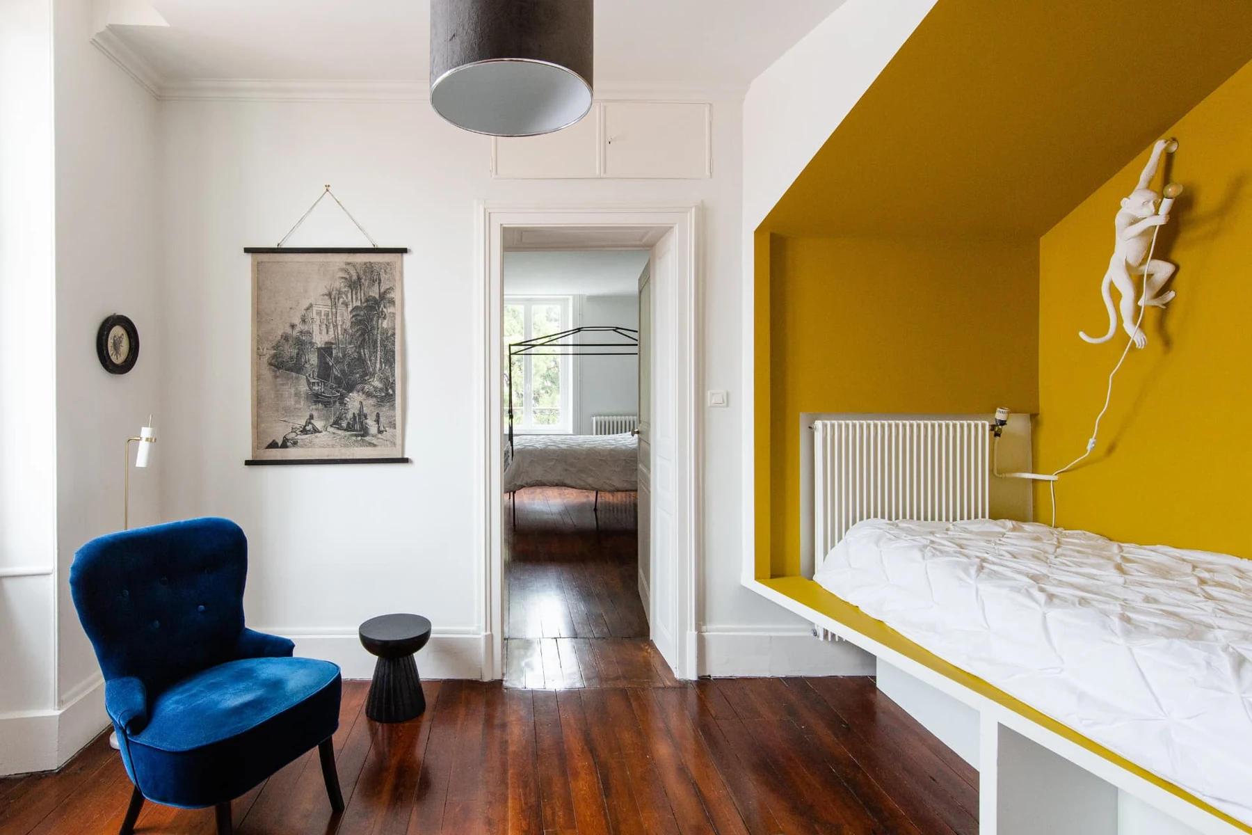Chambre 2, lit cabane dans son alcôve jaune mirabelle, lampe singe et fauteuil bleu