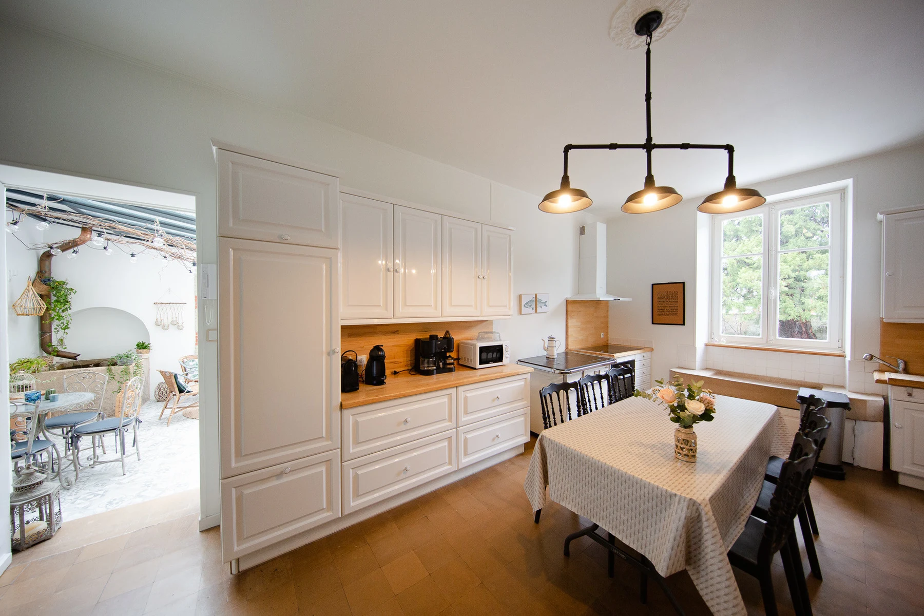 La cuisine ouverte sur la véranda : meubles blancs, plan de travail en bois et guirlandes lumineuses