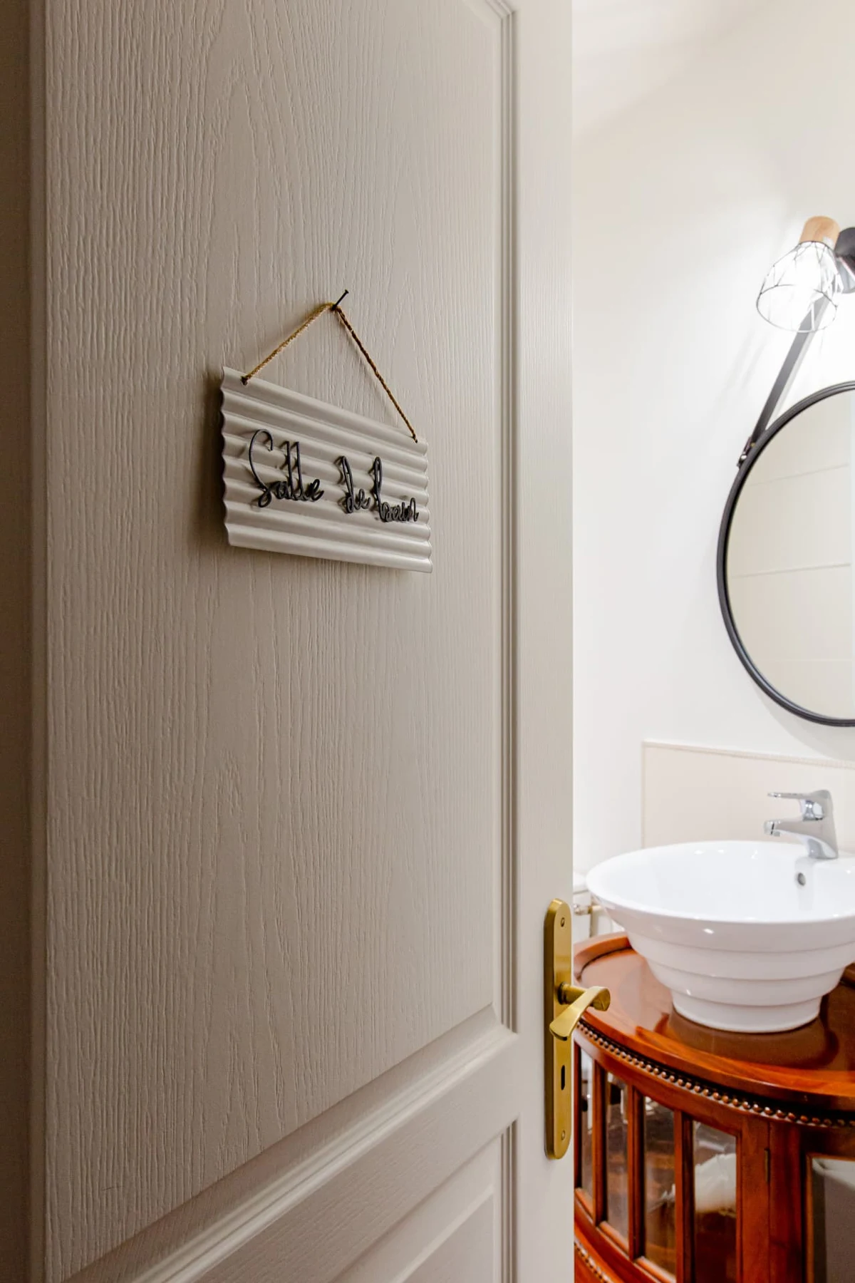 Porte de la salle de bain et sa plaque « Salle de bain », vasque en porcelaine sur meuble ancien