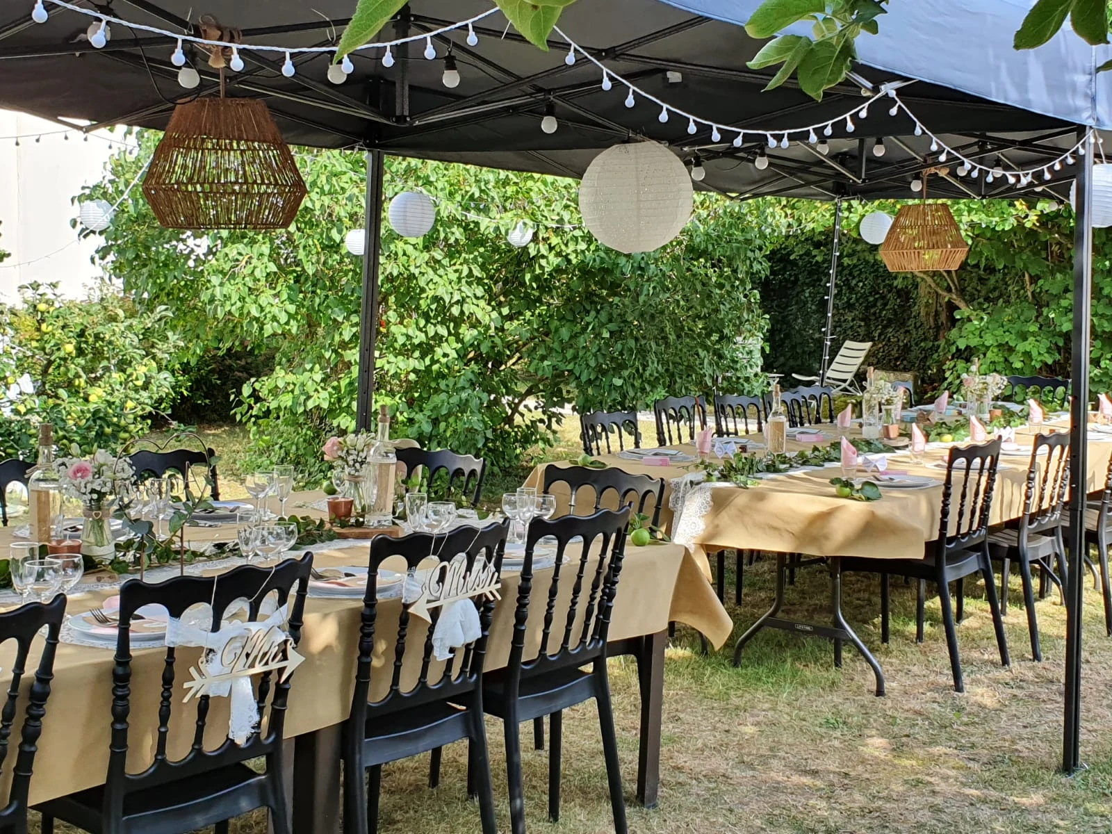 Tables de mariage dressées sous le barnum, chemins de table kraft et lampions suspendus